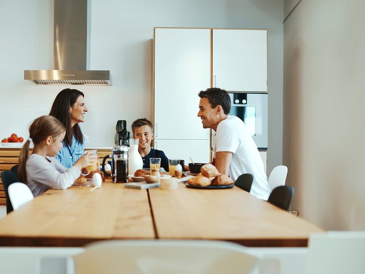 Familie sitzt am Esstisch und frühstücken