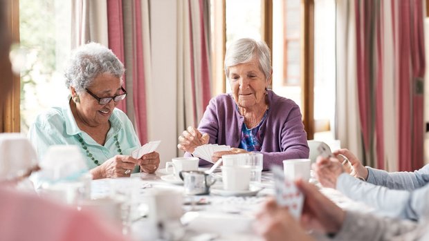Senioren spielen Karten an einem Tisch